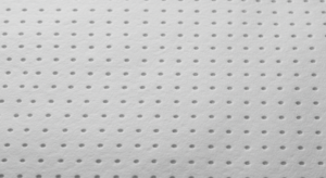 Close-up image of a roll of soft, white perforated nonwoven fabric. The fabric shows clearly defined, evenly spaced perforations, indicating high-quality manufacturing. The material appears smooth and breathable, suitable for use in feminine hygiene products or other sensitive applications.