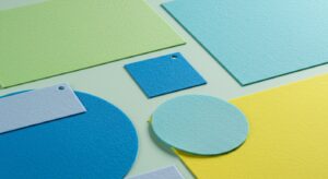 "Close-up shot showcasing a variety of precisely die-cut nonwoven sheets in various shapes, sizes, and colors. Examples include circular medical pads, rectangular filter components, and intricately shaped automotive parts. The image highlights the precision and versatility of Favourite Fab's die-cutting services."