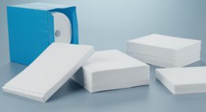 A neatly stacked pile of precisely cut, sterile nonwoven sheets ready for medical applications. The sheets are uniform in size and show clean edges, highlighting the precision cutting process.